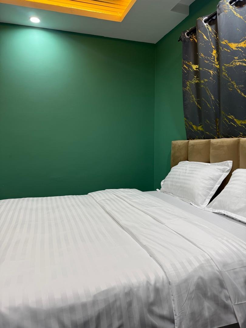Warmly lit lodge bedroom with green walls and crisp white linen